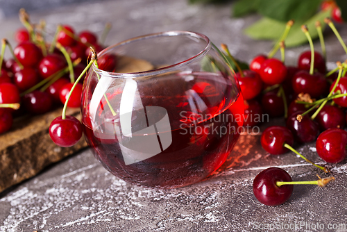Image of Cherry juice in a glass and fresh cherries on a table