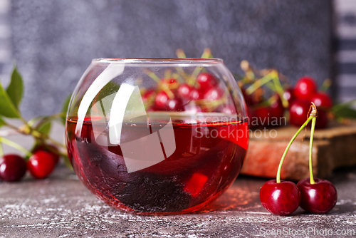 Image of Cherry juice in a glass and fresh cherries on a table