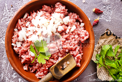 Image of Homemade minced meat with ingredients for making in a bowl over dark slate, stone or concrete background.