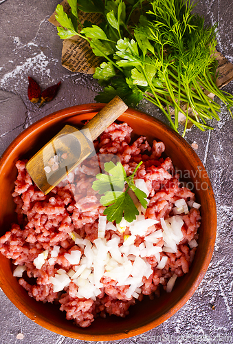 Image of Homemade minced meat with ingredients for making in a bowl over dark slate, stone or concrete background.