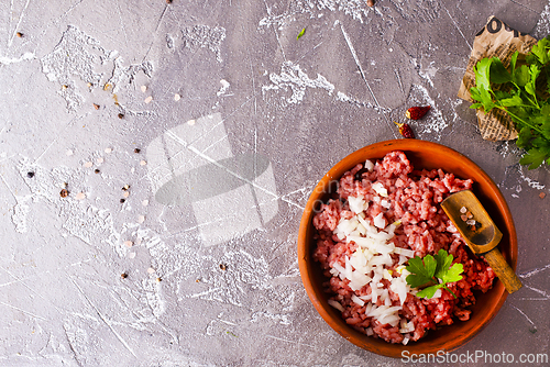 Image of Homemade minced meat with ingredients for making in a bowl over dark slate, stone or concrete background.