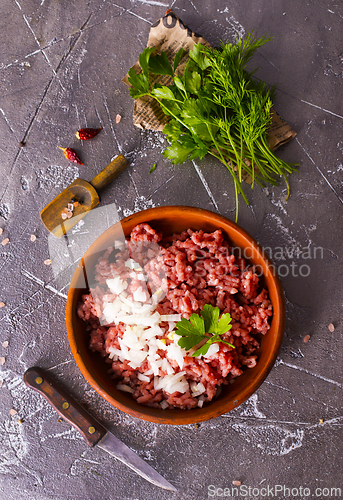 Image of Homemade minced meat with ingredients for making in a bowl over dark slate, stone or concrete background.