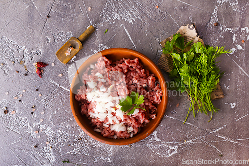 Image of Homemade minced meat with ingredients for making in a bowl over dark slate, stone or concrete background.
