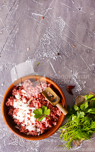 Image of Homemade minced meat with ingredients for making in a bowl over dark slate, stone or concrete background.