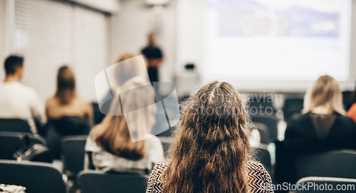 Image of Speaker giving a talk in conference hall at business event. Rear view of unrecognizable people in audience at the conference hall. Business and entrepreneurship concept.