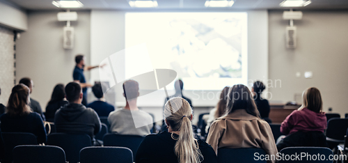 Image of Speaker giving a talk in conference hall at business event. Rear view of unrecognizable people in audience at the conference hall. Business and entrepreneurship concept.
