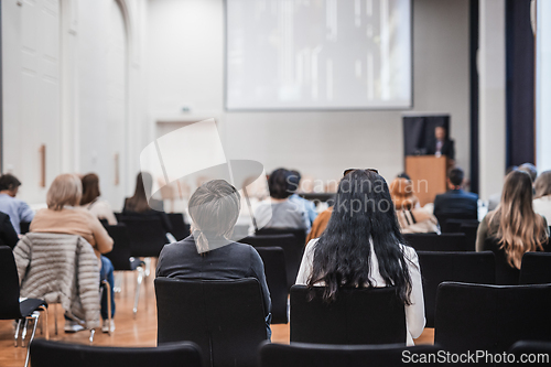 Image of Speaker giving a talk in conference hall at business event. Rear view of unrecognizable people in audience at the conference hall. Business and entrepreneurship concept.
