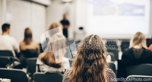 Image of Speaker giving a talk in conference hall at business event. Rear view of unrecognizable people in audience at the conference hall. Business and entrepreneurship concept.