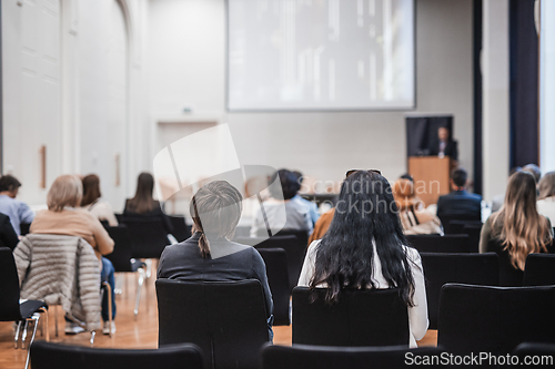 Image of Speaker giving a talk in conference hall at business event. Rear view of unrecognizable people in audience at the conference hall. Business and entrepreneurship concept.