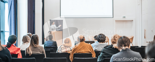 Image of Speaker giving a talk in conference hall at business event. Rear view of unrecognizable people in audience at the conference hall. Business and entrepreneurship concept.