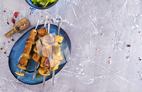 Image of Lamb shish kebab with pieces of onion. kebab and salad on a table