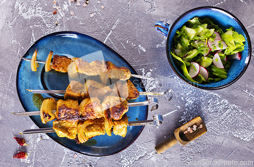 Image of Lamb shish kebab with pieces of onion. kebab and salad on a table