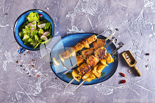 Image of Lamb shish kebab with pieces of onion. kebab and salad on a table