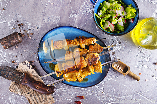 Image of Lamb shish kebab with pieces of onion. kebab and salad on a table