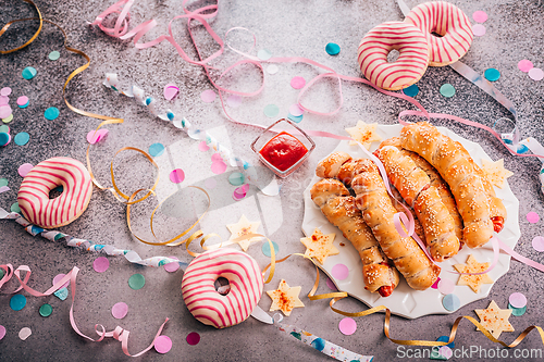 Image of Long sausages wrapped in yeast dough with donuts - traditional carnival, Fasching and party food