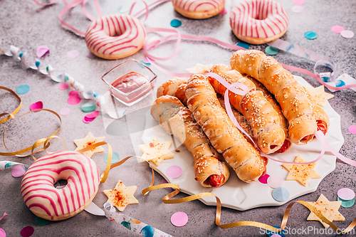 Image of Long sausages wrapped in yeast dough with donuts - traditional carnival, Fasching and party food