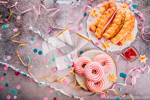 Image of Long sausages wrapped in yeast dough with donuts - traditional carnival, Fasching and party food