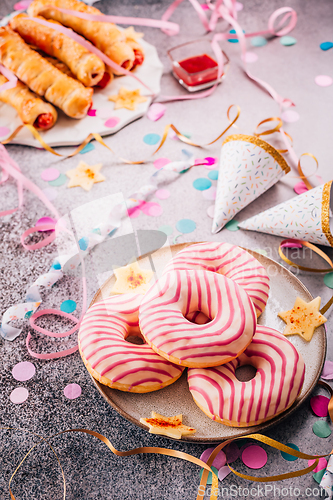 Image of Long sausages wrapped in yeast dough with donuts - traditional carnival, Fasching and party food