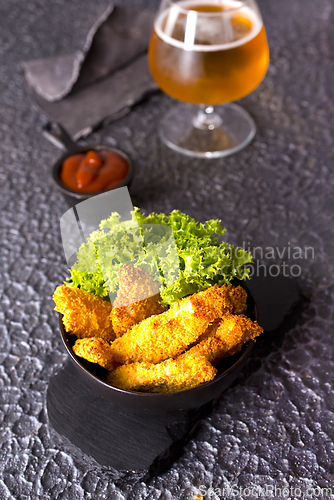 Image of There is a plate of crispy chicken nuggets on the table. Fast food.