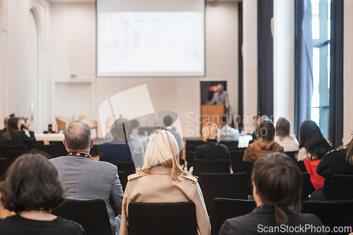 Image of Speaker giving a talk in conference hall at business event. Rear view of unrecognizable people in audience at the conference hall. Business and entrepreneurship concept.