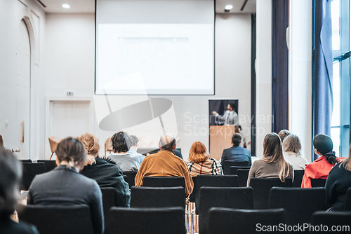 Image of Speaker giving a talk in conference hall at business event. Rear view of unrecognizable people in audience at the conference hall. Business and entrepreneurship concept.