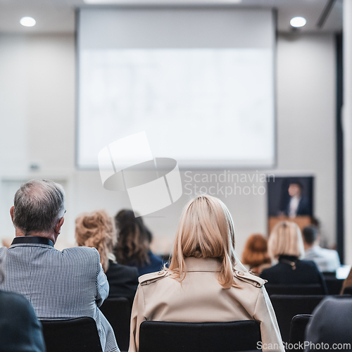 Image of Speaker giving a talk in conference hall at business event. Rear view of unrecognizable people in audience at the conference hall. Business and entrepreneurship concept.