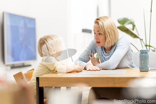 Image of Caring young Caucasian mother and small son drawing painting in notebook at home together. Loving mom or nanny having fun learning and playing with her little 1,5 year old infant baby boy child.