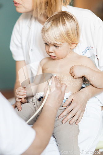 Image of Small child being checked for heart murmur by heart ultrasound exam by cardiologist as part of regular medical checkout at pediatrician.