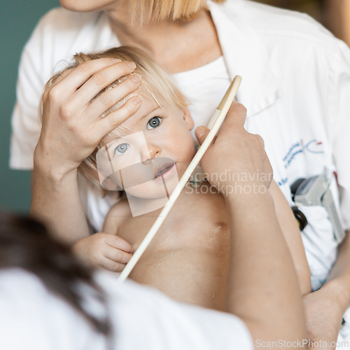 Image of Small child being checked for heart murmur by heart ultrasound exam by cardiologist as part of regular medical checkout at pediatrician.