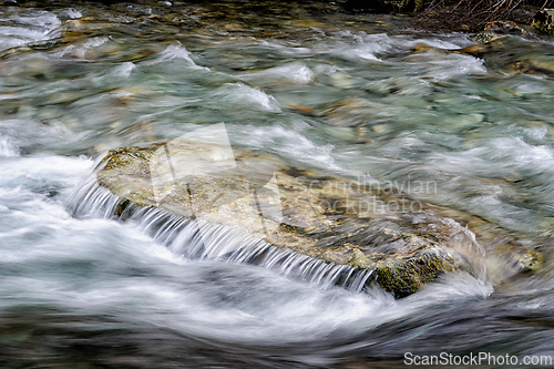 Image of Flowing river water cascading over smooth stones in Norway's tra