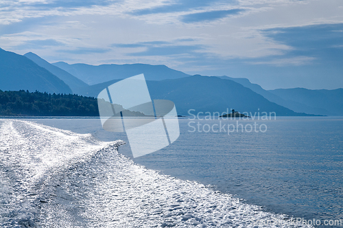 Image of Serene waters reflect blue skies as a boat glides through Norway