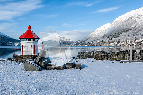 Image of Winter tranquility by the fjord with a charming lighthouse stand