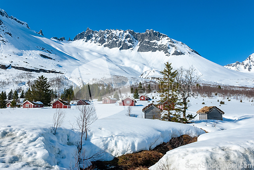 Image of Snow-covered village nestled in majestic mountains during a brig