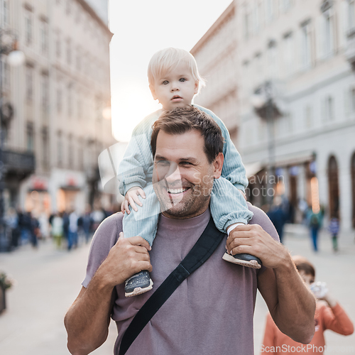 Image of Portrait of smiling father carrying his toddler child piggyback around city on family vacations. Happy father's day.