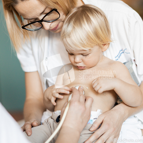 Image of Small child being checked for heart murmur by heart ultrasound exam by cardiologist as part of regular medical checkout at pediatrician.