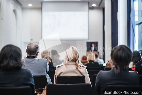 Image of Speaker giving a talk in conference hall at business event. Rear view of unrecognizable people in audience at the conference hall. Business and entrepreneurship concept.