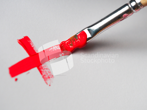 Image of A paintbrush painting a red X