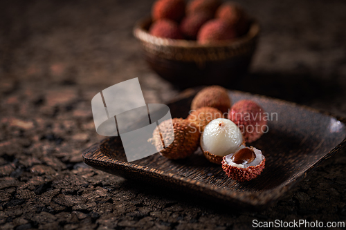 Image of Fresh lychees are served on a wooden tray