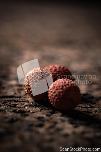 Image of Three lychees sit on cracked dark surface