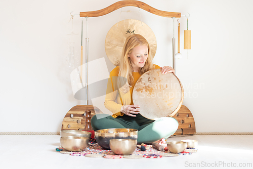 Image of Young cheerful woman performing music therapy session with traditional instruments. Sound meditation, body healing. Seven chakras. Healthcare recreation process.