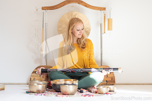 Image of Young cheerful woman performing music therapy session with traditional instruments. Sound meditation, body healing. Seven chakras. Healthcare recreation process.