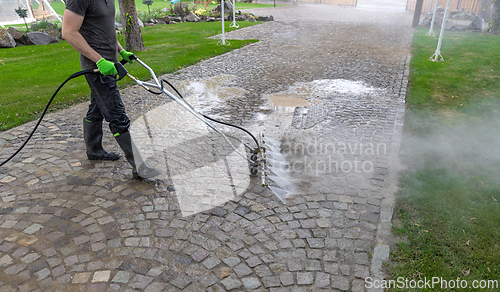 Image of Professional cleaning service worker washing cobblestone