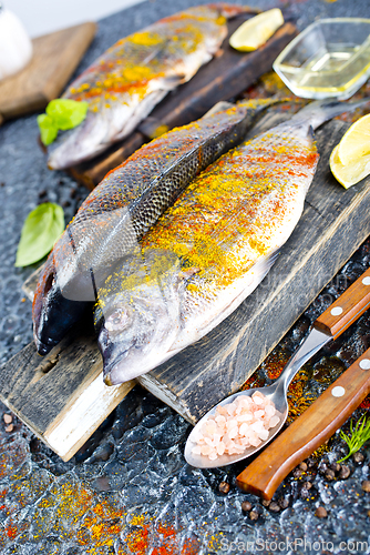 Image of Fresh raw dorado fish cooking with lemon and spice.