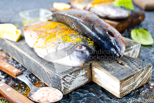 Image of Fresh raw dorado fish cooking with lemon and spice.