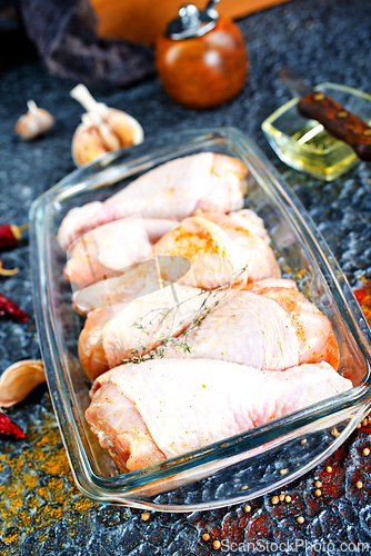 Image of Raw chicken drumsticks with seasonings in glass plate. Chicken legs ready to cook.