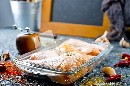 Image of Raw chicken drumsticks with seasonings in glass plate. Chicken legs ready to cook.