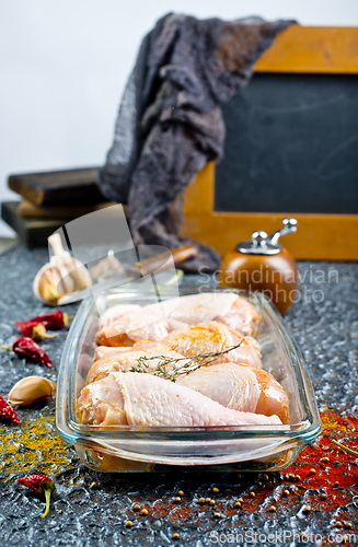 Image of Raw chicken drumsticks with seasonings in glass plate. Chicken legs ready to cook.
