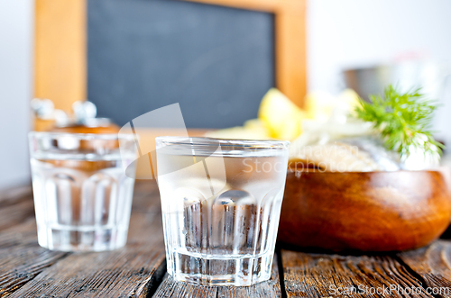 Image of one empty second vodka-filled glass surrounded by a snack with herring and onions