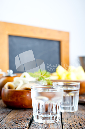 Image of one empty second vodka-filled glass surrounded by a snack with herring and onions