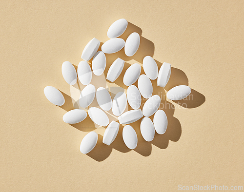 Image of white pills on beige background